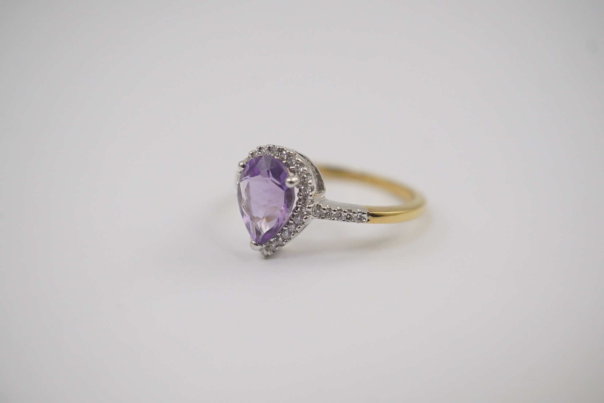 A modern 18ct gold and single stone pear cut amethyst set ring, with diamond chip set border and shoulders, size O, gross weight 3.4 grams. Condition - fair to good